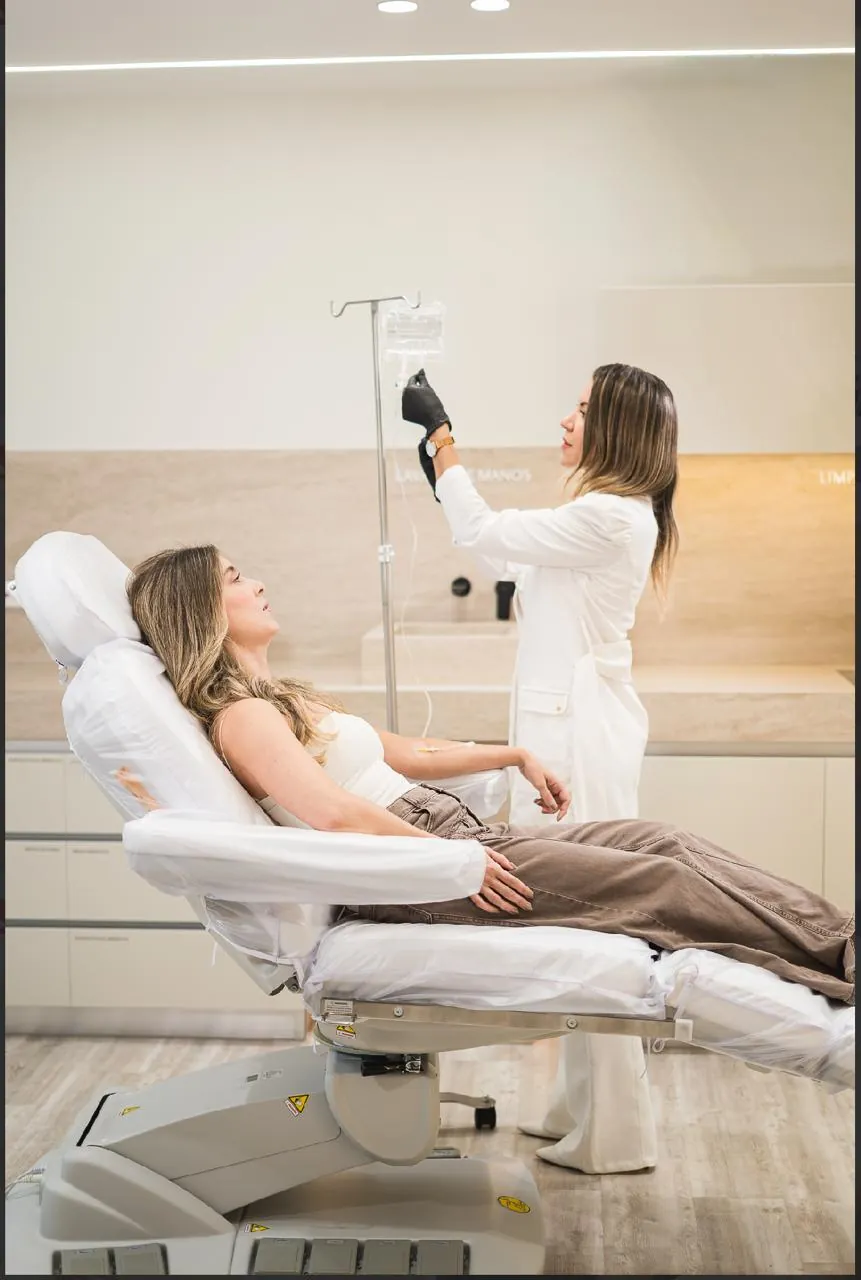 Patient receiving an intravenous infusion in a treatment chair while a clinician adjusts the drip at the Medellín clinic